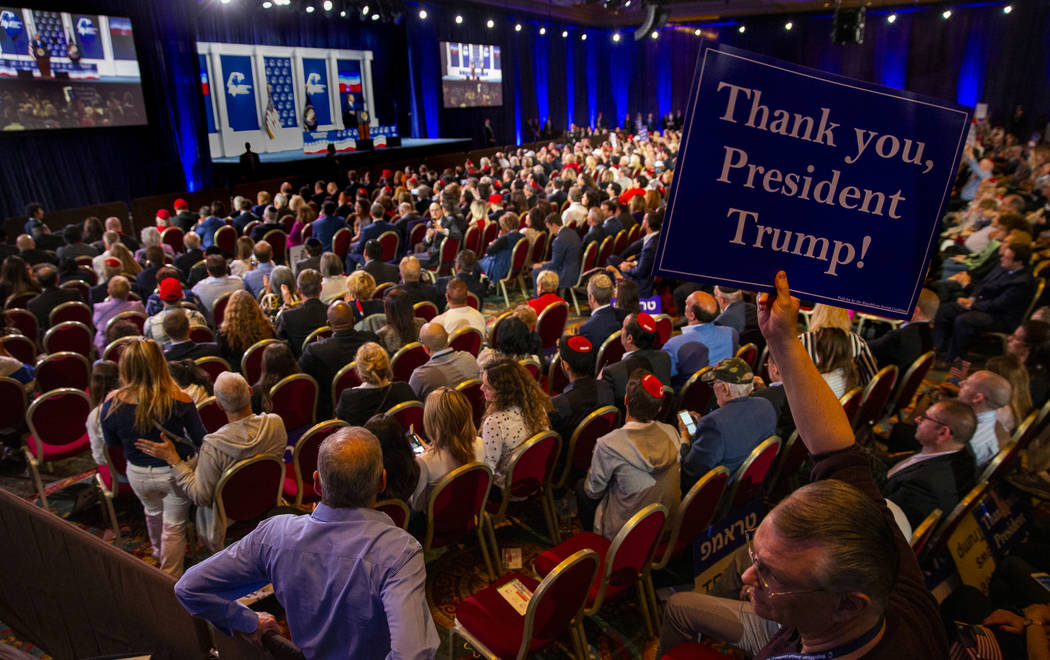 An attendee holds up a sign as President Donald J. Trump addresses the Republican Jewish Coalit ...