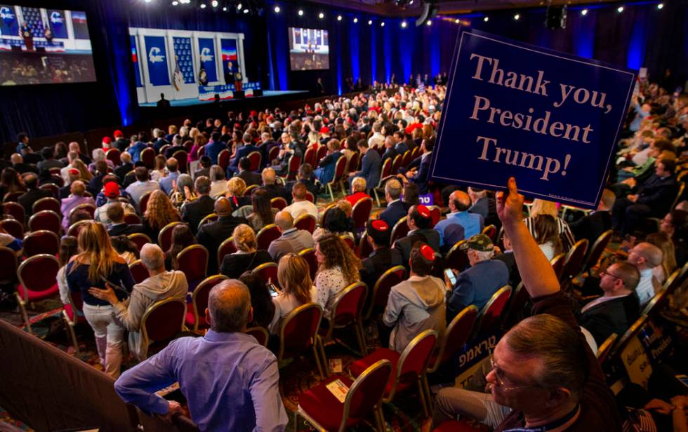 An attendee holds up a sign as President Donald J. Trump addresses the Republican Jewish Coalit ...