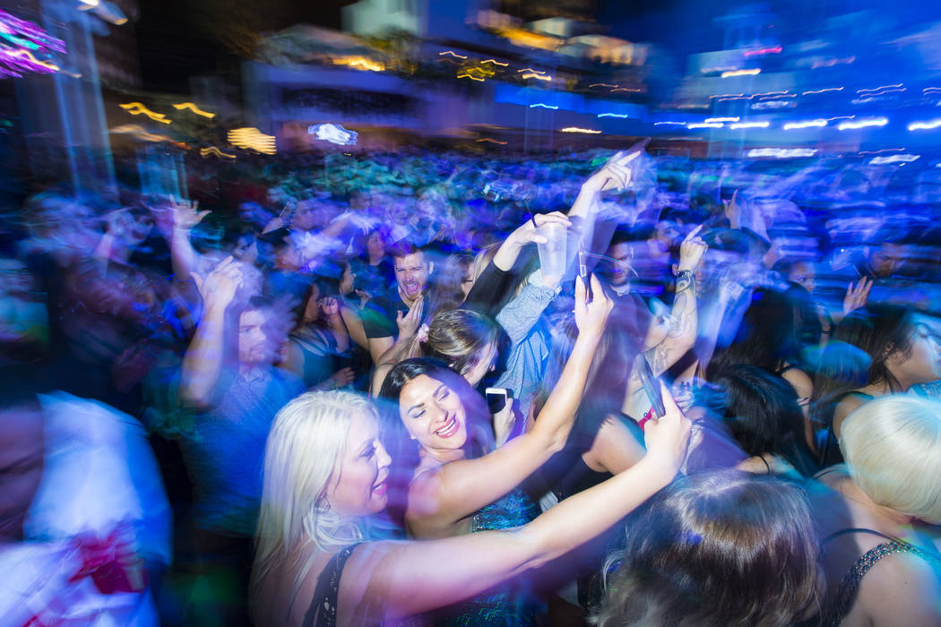 Attendees record with their phones as performers entertain by the outdoor stage during the gran ...