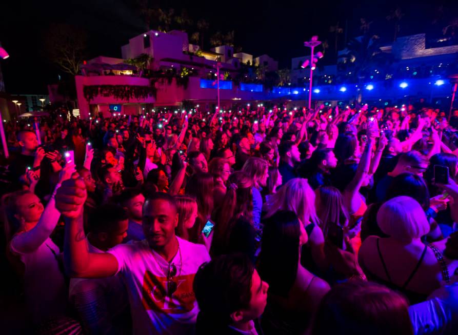 Attendees hold up phones and lighters in memory of Nipsey Hussle during the grand opening weeke ...