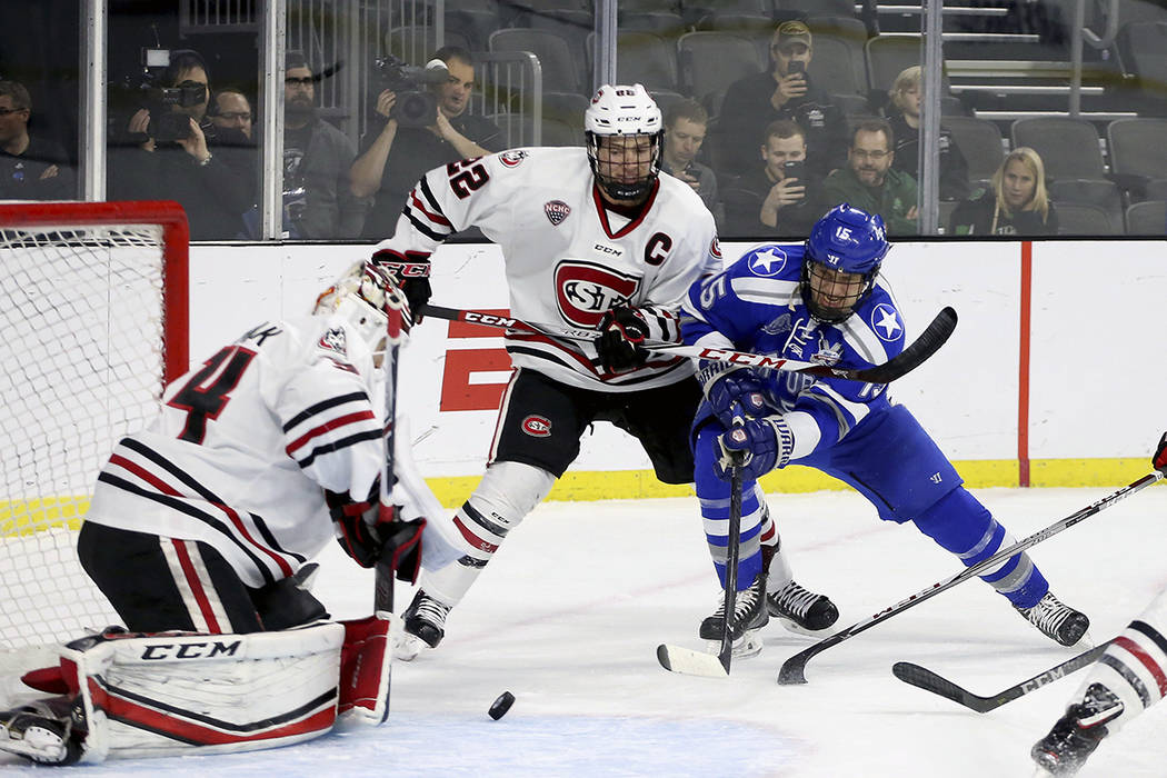 Air Force's Evan Giesler (15) battles to get the puck past St. Cloud State goalie David Hrenak ...