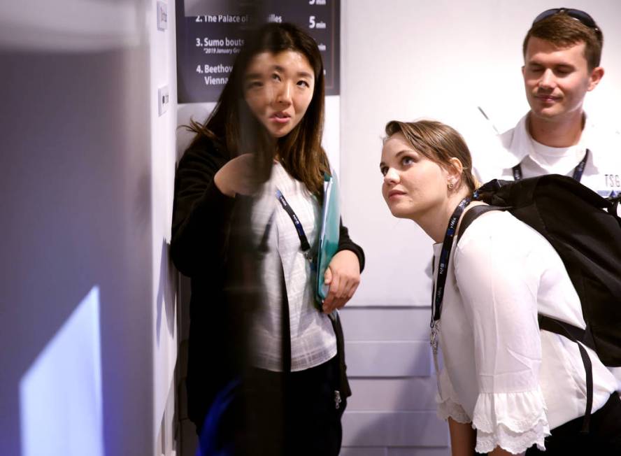 Yumiko Takahashi of Cosmomedia America/NHK, left, shows a 1mm thick 8K TV system used in conjun ...