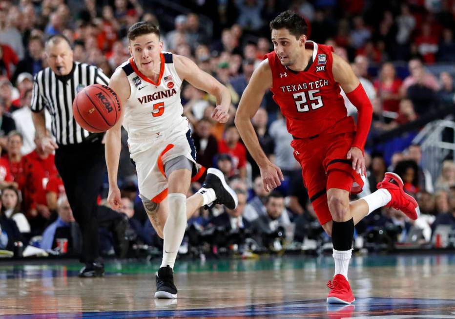 Virginia's Kyle Guy (5) and Texas Tech's Davide Moretti (25) chase a loose ball during the over ...