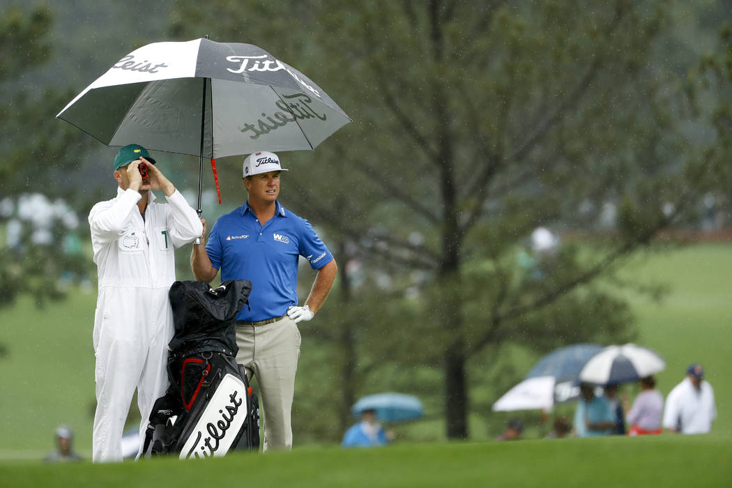 Charley Hoffman, right, and his caddie stand on the first hole fairway in the rain during a pra ...