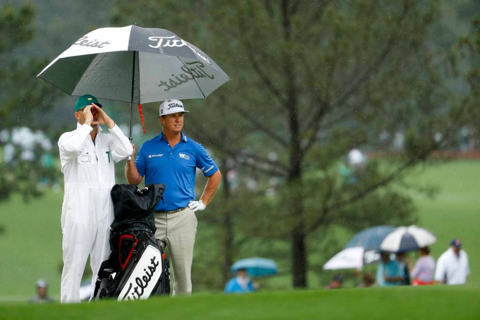 Charley Hoffman, right, and his caddie stand on the first hole fairway in the rain during a pra ...