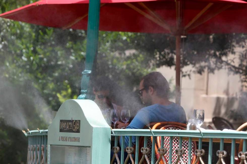 Tourists are seen on a hot day through misters as they sit outside Mon Ami Gabi restaurant at P ...