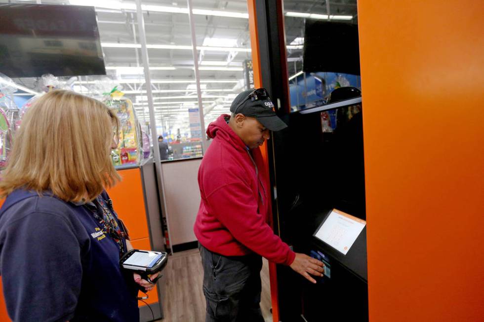 Walmart Associate Molly watches Harold Lloyd scan for his order at the pickup tower at the Walm ...