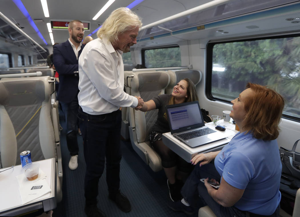 Richard Branson, of Virgin Group, center, greets a passenger while riding a Brightline train fr ...