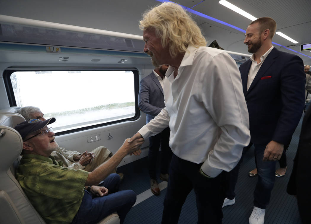 Richard Branson, of Virgin Group, center, greets a passenger while riding a Brightline train fr ...