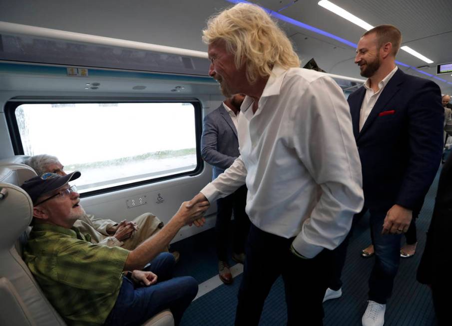 Richard Branson, of Virgin Group, center, greets a passenger while riding a Brightline train fr ...