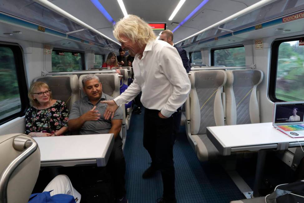 Richard Branson, of Virgin Group, center, greets a passenger while riding a Brightline train fr ...