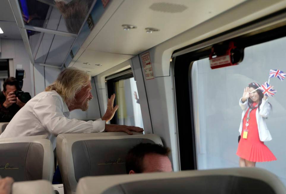 An employee holding British flags waves as Richard Branson, of Virgin Group, left, departs on a ...