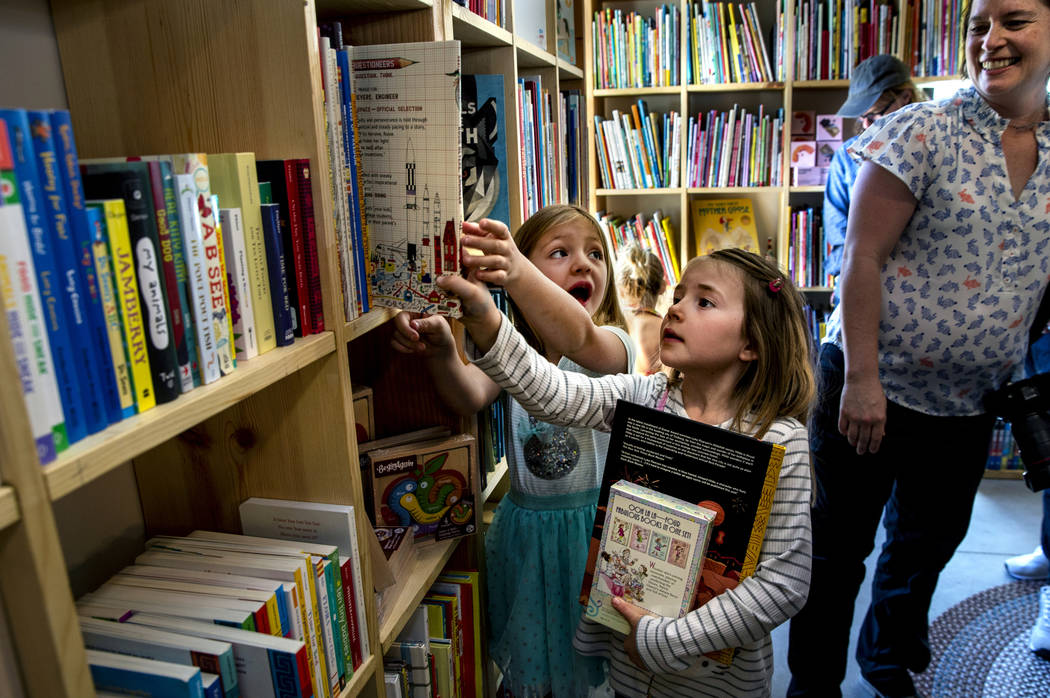 Greta Henderson, 7, and a friend check out all the great books for sale in the young reader's s ...