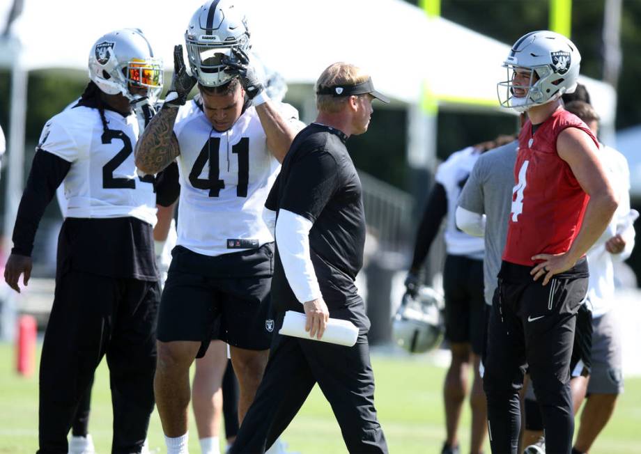 Oakland Raiders head coach Jon Gruden walks past running back Marshawn Lynch (24), left, runnin ...