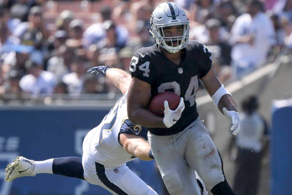 Oakland Raiders running back Chris Warren runs past Los Angeles Rams defensive end Brian Womac ...