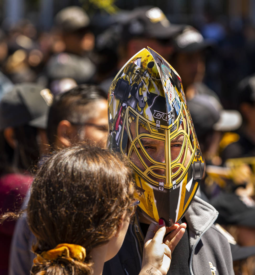A fan wears a cardboard mask as he and others send off the Golden Knights players departing Cit ...