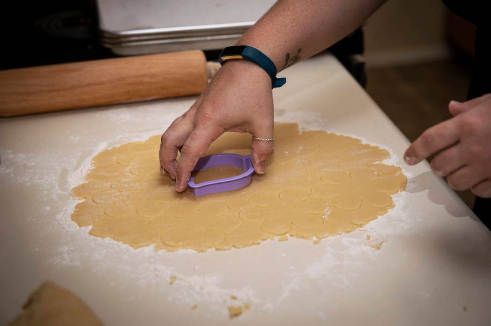 Owner of Cakes, Cookies and Creations Jessica Dejarnett cuts out shapes from cookie dough to ba ...