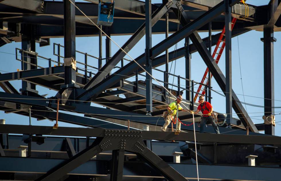 Crews work move the newest truss into place as its slowly lowered and attached into place atop ...