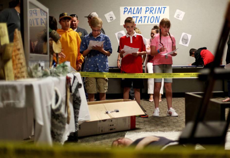 Children examine a fake crime scene for the coroner office's Take Our Daughters and Sons to Wor ...