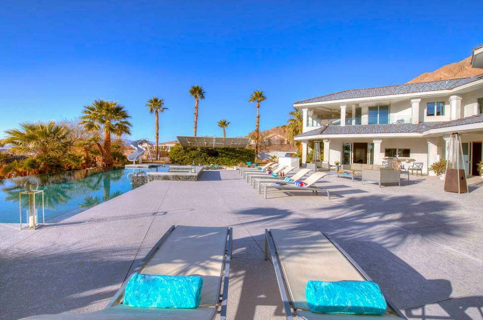 The pool area has a water slide and mature palm trees. (Sotherby’s International Realty, Synergy)