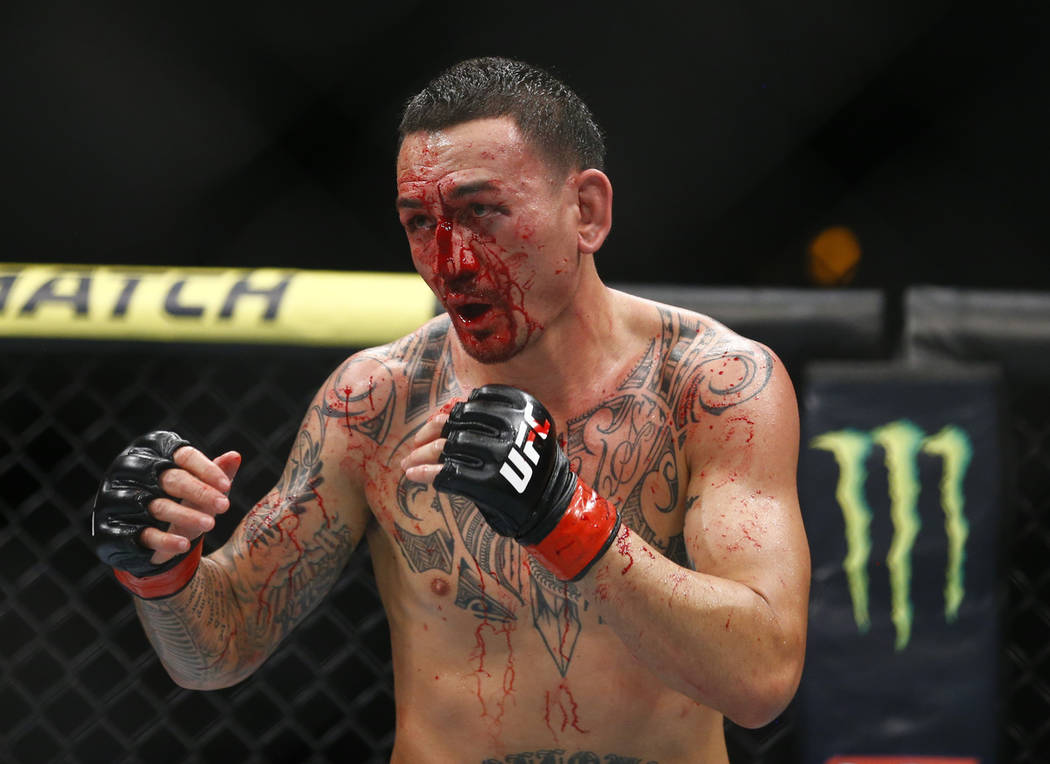 Max Holloway fights Dustin Poirier during an interim lightweight title mixed martial arts bout ...