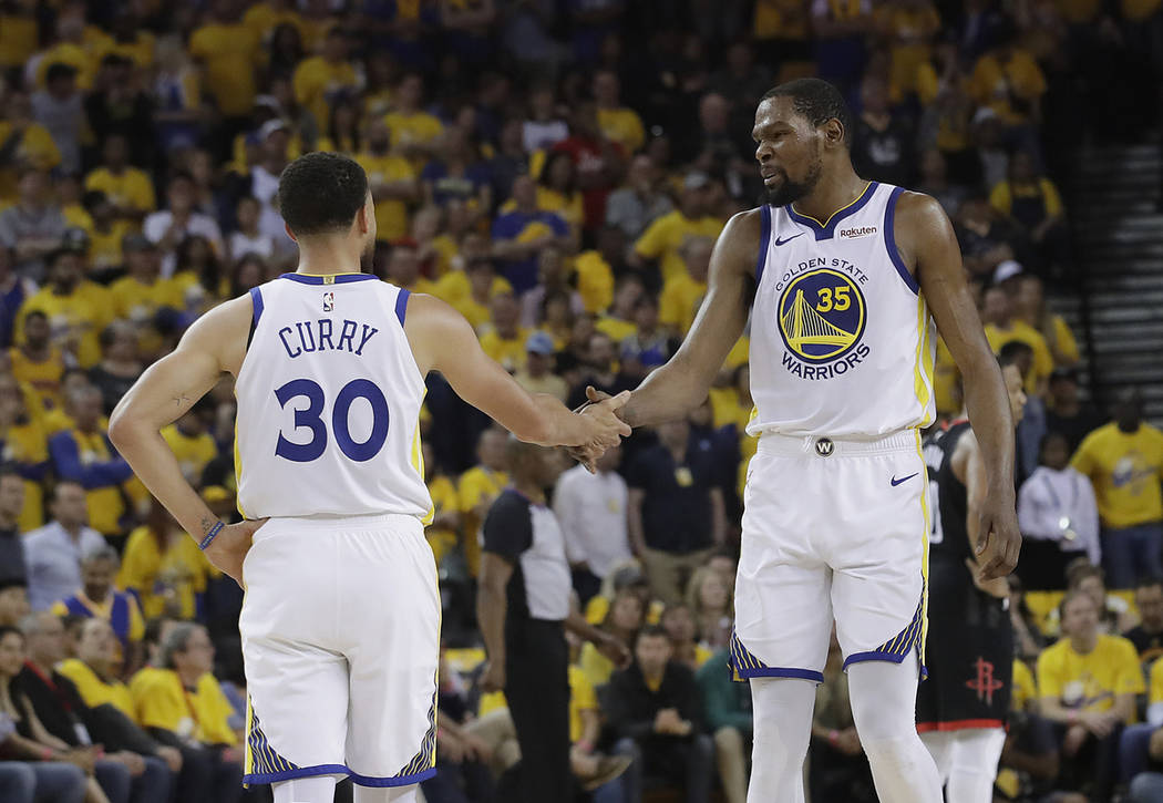 Golden State Warriors guard Stephen Curry (30) reacts with forward Kevin Durant (35) during the ...
