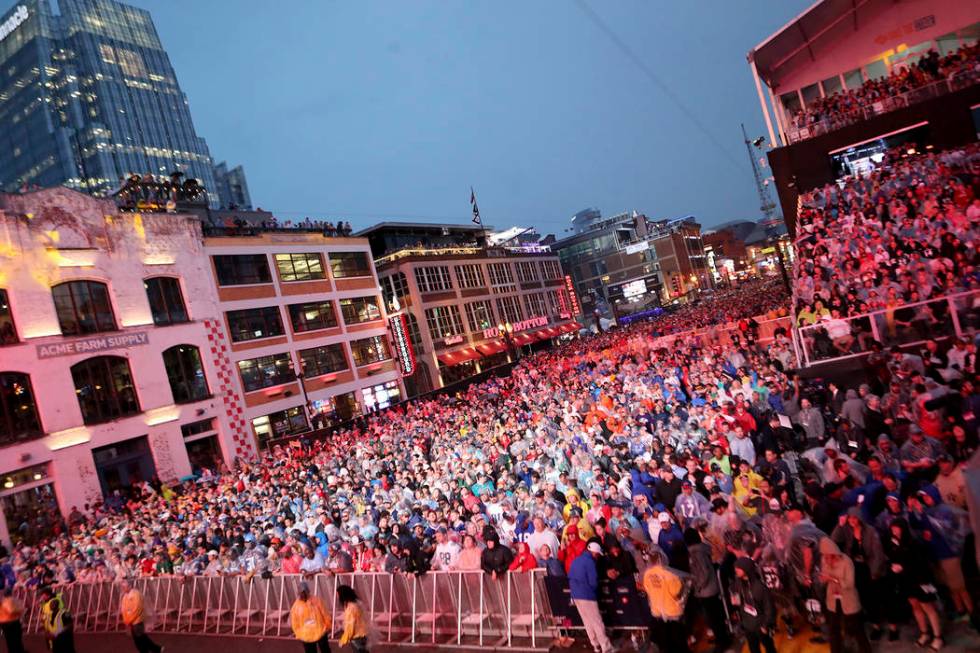 Fans line up Broadway in the rain to watch the first round of the NFL football draft, in Nashvi ...