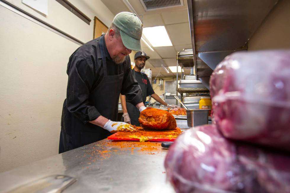 New employee Ron Cochran adds some rub to a large brisket during training from kitchen prep/smo ...