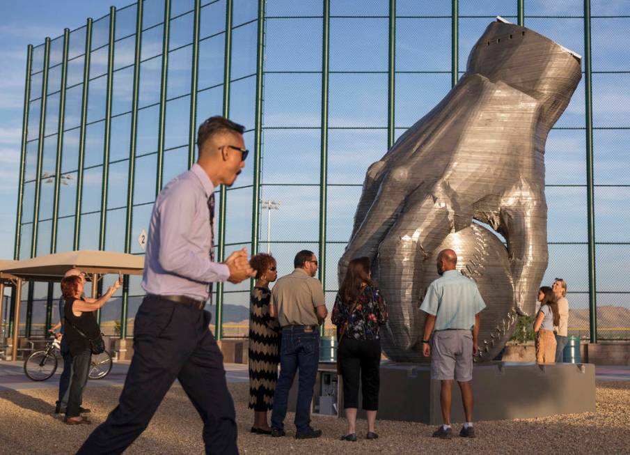 Artist Luis Varela-Rico, left, passes by his sculpture "Organic Study No. 2" during a ...