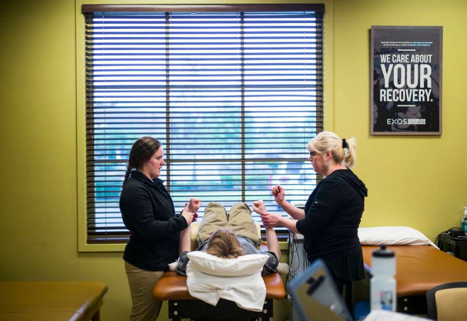 Student physical therapist Meghan Bell, left, demonstrates an excercise on Grayson McClure, cen ...