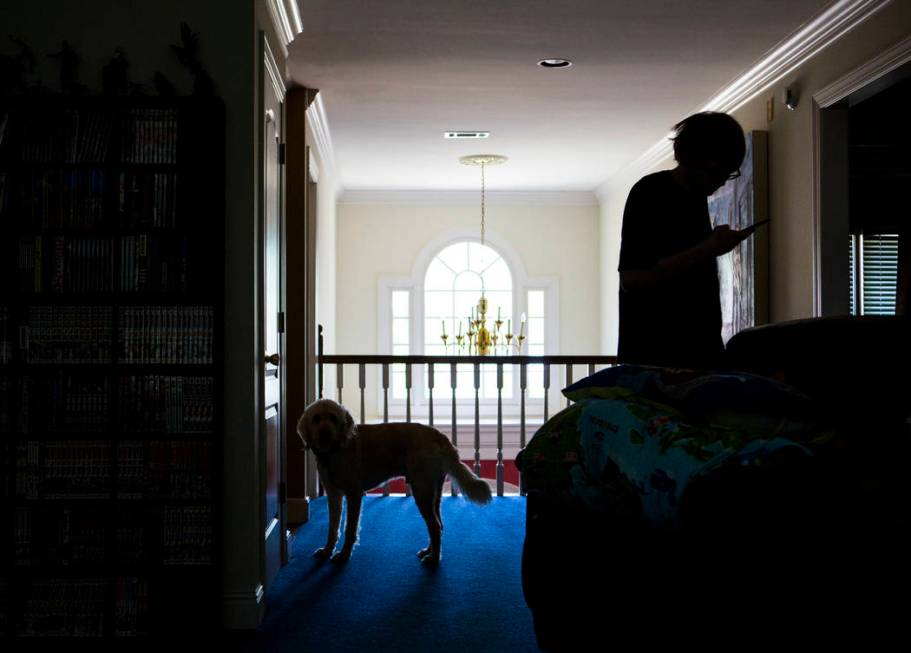 Grayson McClure checks his phone while standing next to his dog, Yojimbo, at the McClure's home ...