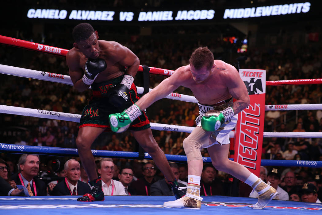 Saul "Canelo" Alvarez, right, throws a punch against Daniel Jacobs in the WBC, WBA, I ...