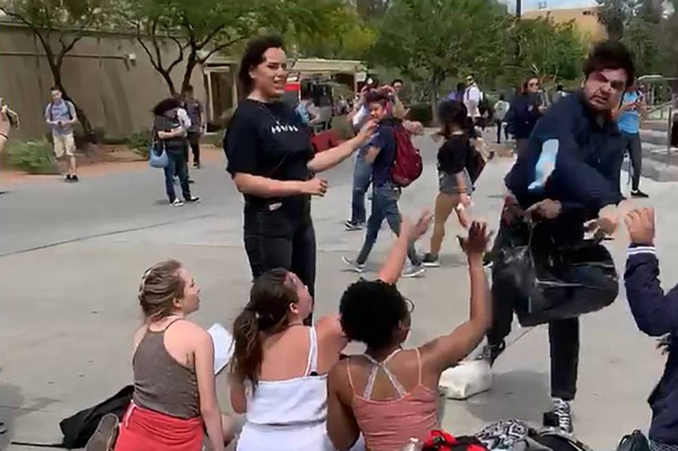 An unidentified male throws a granola bar at students working at a Turning Point USA booth at U ...