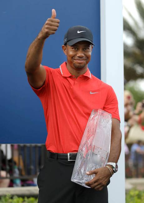 FILE - In this May 12, 2013, file photo, Tiger Woods gives a thumbs-up as he holds the trophy a ...