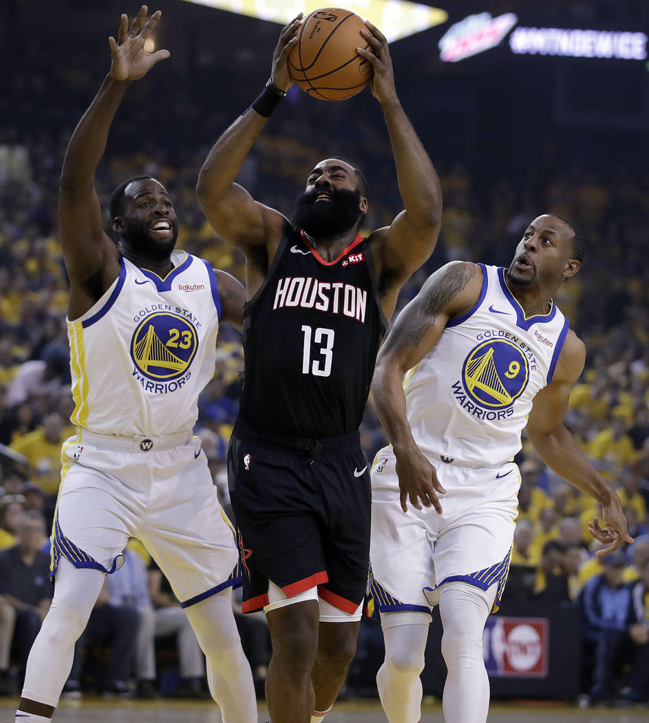 Houston Rockets' James Harden, center, looks to shoot between Golden State Warriors' Draymond G ...