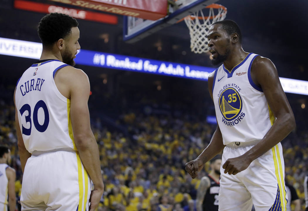 Golden State Warriors' Kevin Durant, right, speaks with Stephen Curry (30) after Curry was call ...