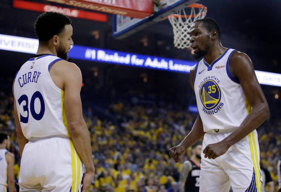 Golden State Warriors' Kevin Durant, right, speaks with Stephen Curry (30) after Curry was call ...
