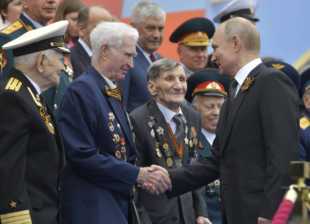 Russian President Vladimir Putin shakes hands with WWII veterans prior to a military parade mar ...