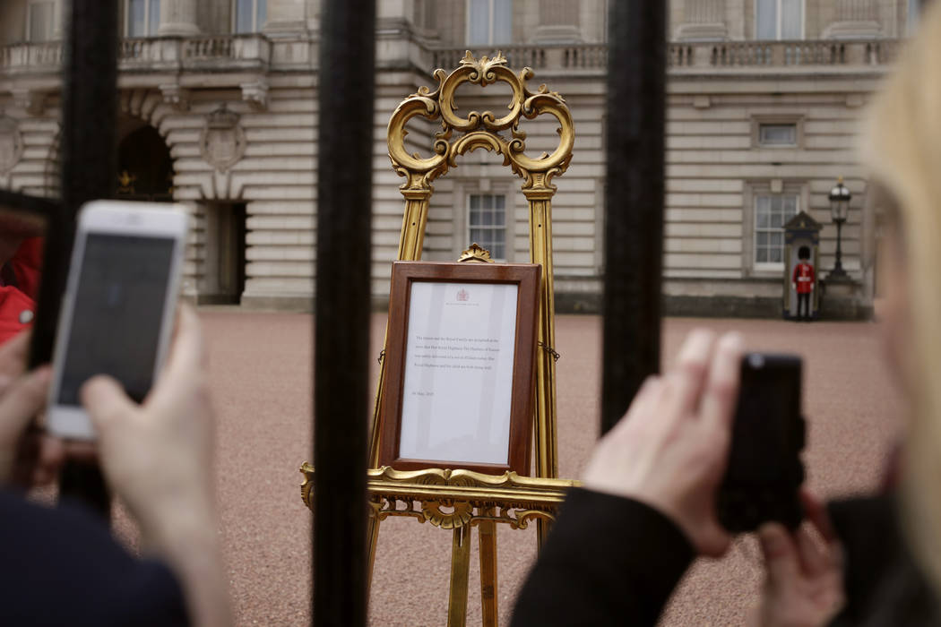 People take pictures of the notice on an easel in the forecourt of Buckingham Palace, London, T ...
