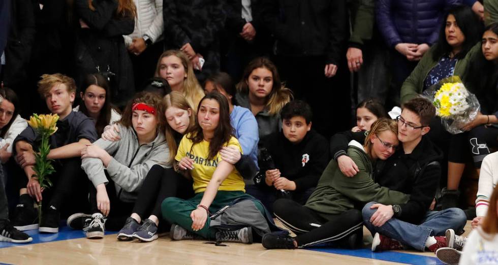 Young people console each other during a community vigil to honor the victims and survivors of ...