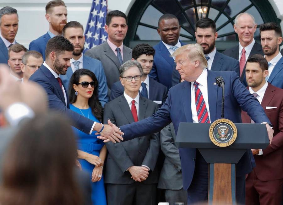 President Donald Trump, right, reaches over to shake hands with outfielder J.D. Martinez, left, ...