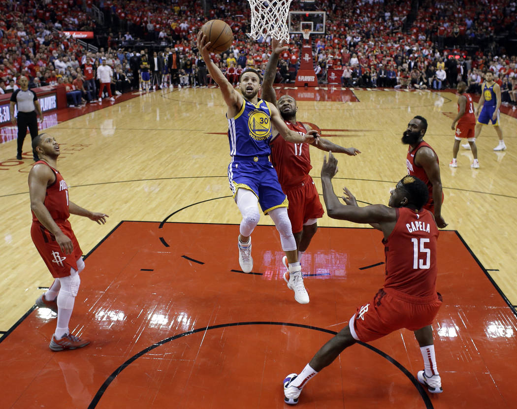 Golden State Warriors' Stephen Curry (30) goes up for a shot between Houston Rockets' Eric Gord ...
