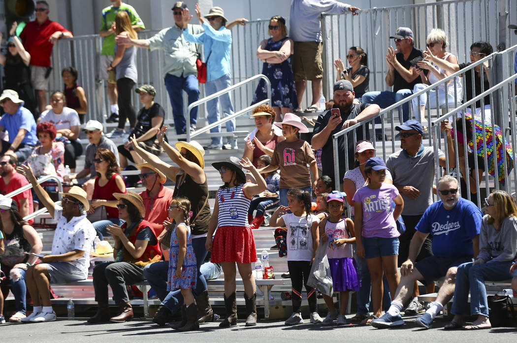 Attendees wave their hands as items are given out by LV.Net during the Helldorado Parade along ...