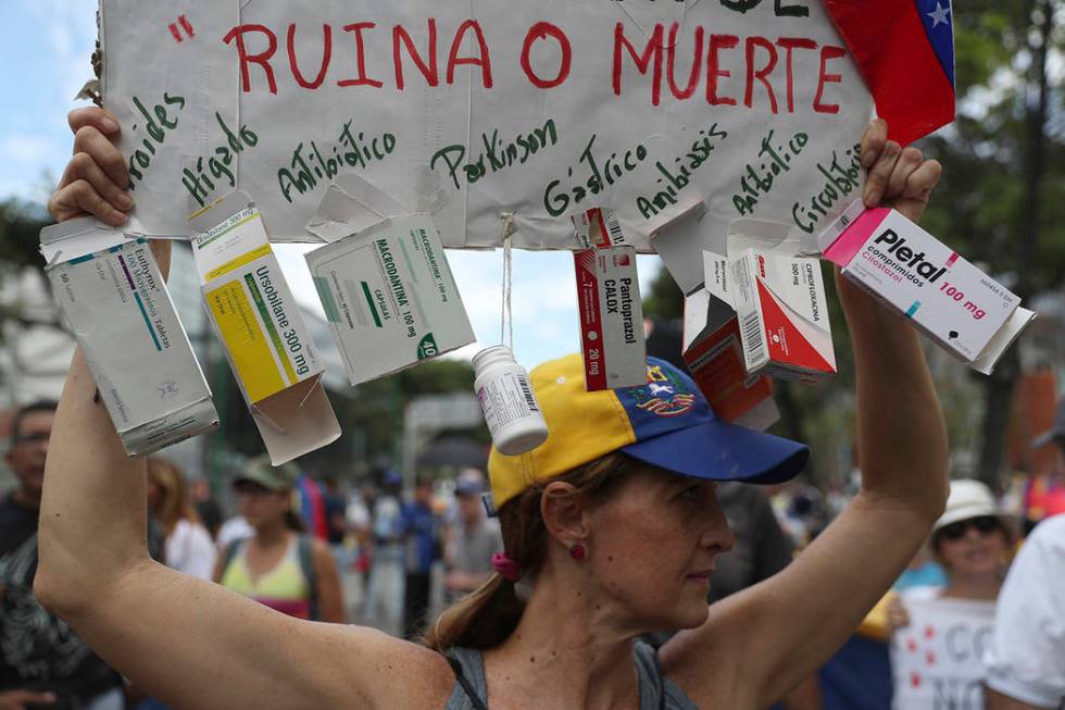 An opponent of the Nicolas Maduro government holds up a homemade poster from which hang empty b ...