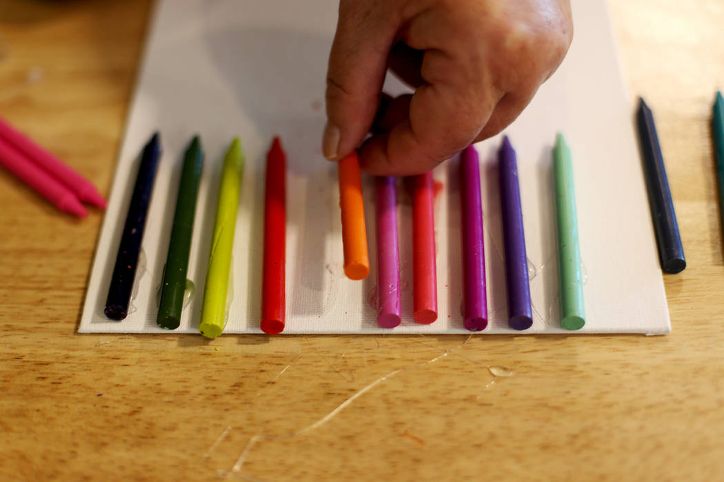 Sandy Windom works on crayon art that will be melted at the Mother's Day Morning of Cookies &am ...