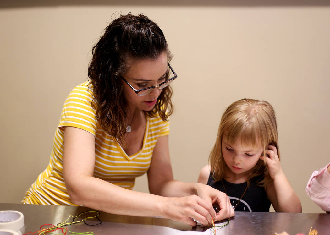 Whitney Jones works on a friendship bracelet with her daughter Penny Jones, 3, at the Mother's ...