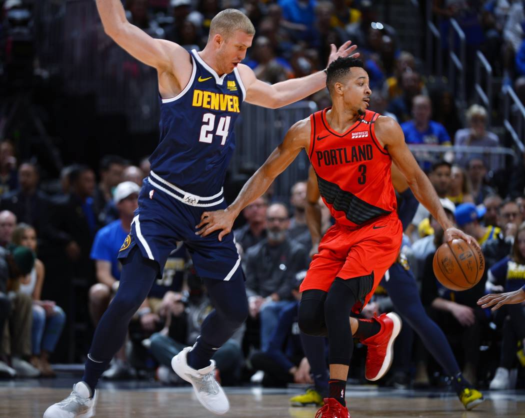 Portland Trail Blazers guard CJ McCollum, right, drives past Denver Nuggets forward Mason Pluml ...