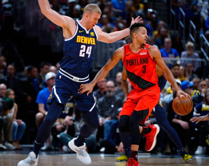 Portland Trail Blazers guard CJ McCollum, right, drives past Denver Nuggets forward Mason Pluml ...