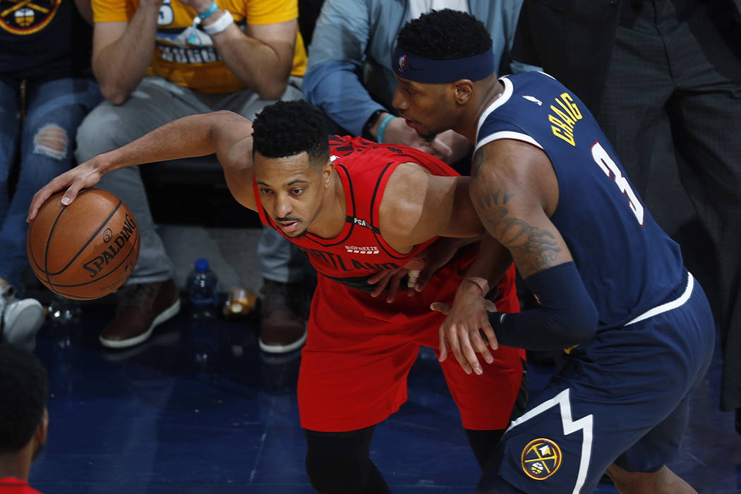 Portland Trail Blazers guard CJ McCollum, left, looks to pass the ball as Denver Nuggets forwar ...