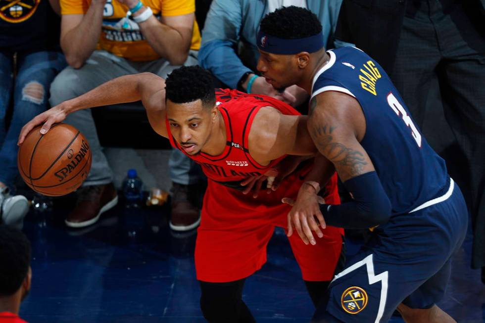 Portland Trail Blazers guard CJ McCollum, left, looks to pass the ball as Denver Nuggets forwar ...